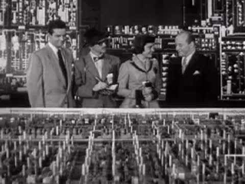People looking at an industrial model display in a room.