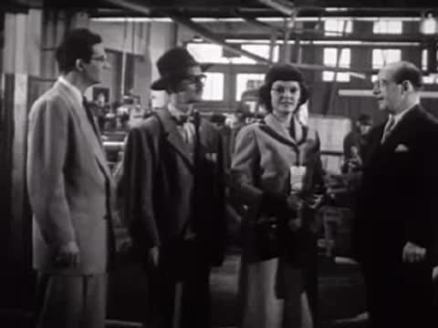 A group of people standing and talking inside a factory.