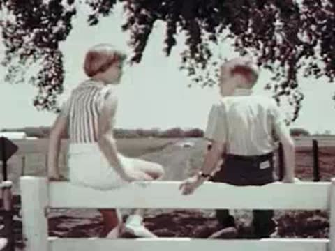 A convertible driving, then two kids sitting on a fence and jumping down.