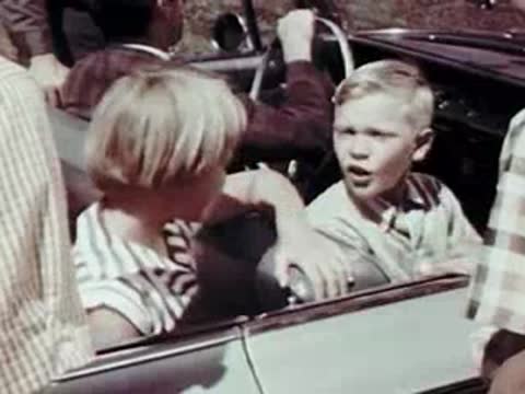 Children sitting inside a car talking and laughing during a trip.