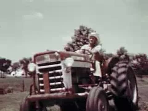 A man driving a red and white tractor across a farm field.