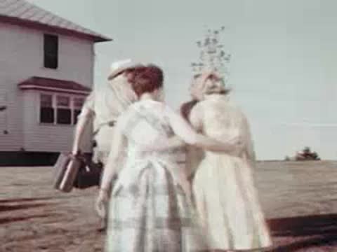 People walking together on the lawn in front of a farmhouse.