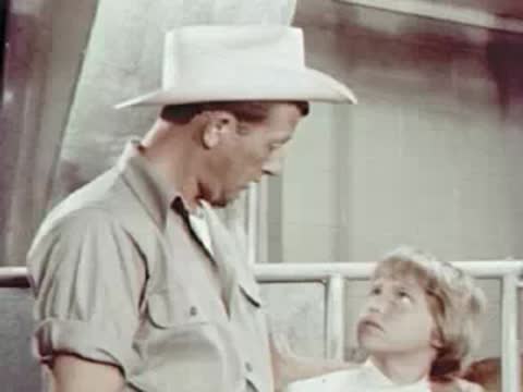 Young boy talking to a man in cowboy hat on a dairy farm