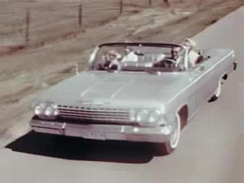 Light-colored convertible driving down a country road on a sunny day.