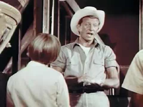 Man holding grain and talking to children in a barn