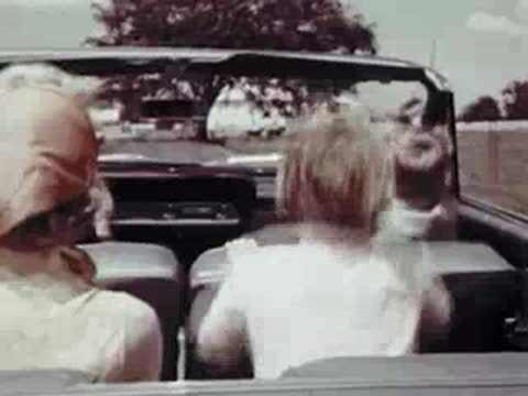 Rear view from inside a convertible showing children and driver enjoying the ride.