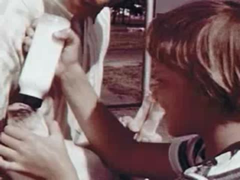 Child feeding a baby pig with a milk bottle.