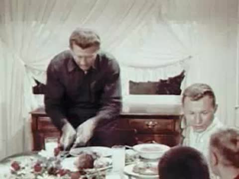 Man at the head of a dining table preparing food.