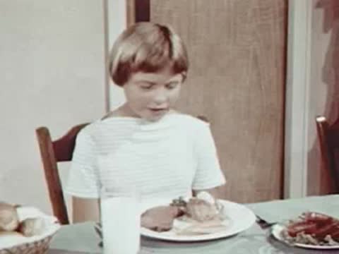 Child sitting at a dining table looking at food.