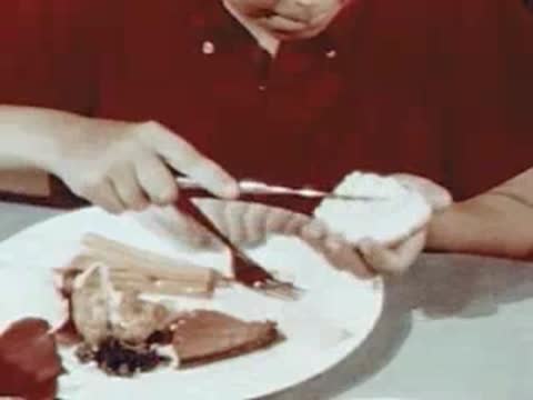 Person spreading butter on a roll at a dinner table.