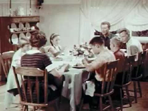 Family eating breakfast together at a dining table, mid-century rural home