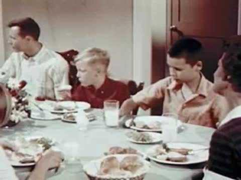 Family seated around a dining table, eating and drinking milk