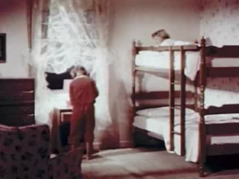 Child looking out the bedroom window near bunk beds