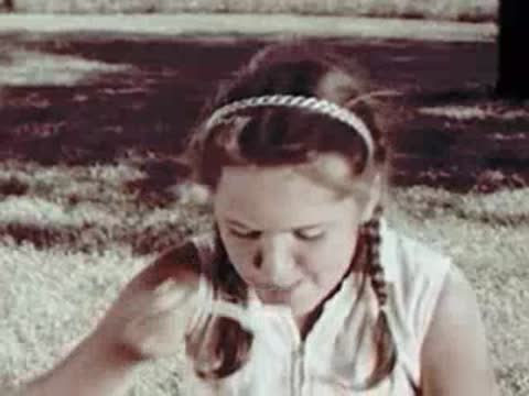 Girl sitting outdoors, eating, mid-century clothing
