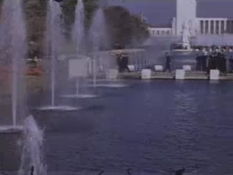 Pan right across fountains spraying water into a large pool on the fairgrounds.