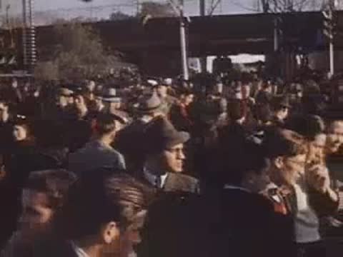 Pan right through a dense crowd of people walking and conversing outdoors.