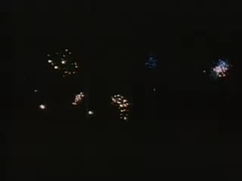 Various nighttime shots of distant fireworks displays sparkling in the dark.