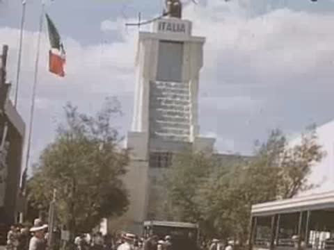 A medium shot of the ITALIA pavilion with Italian flags and people walking.