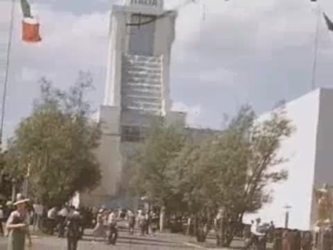 A medium shot of people walking near the ITALIA pavilion with a flag flying.