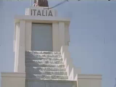 A medium shot of the ITALIA pavilion featuring a staircase waterfall and a statue.