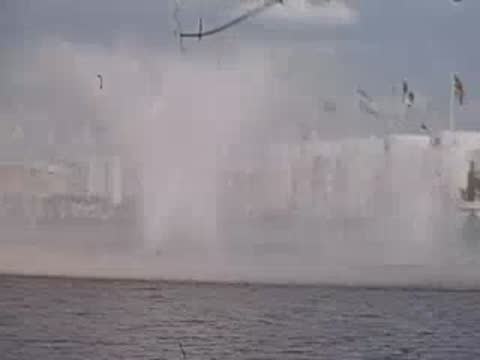 A medium shot of a large fountain spraying water with a pavilion in the background.