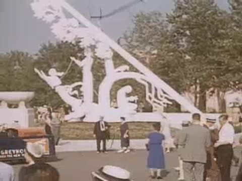 Crowd walking past decorative white structures and pools at the fair