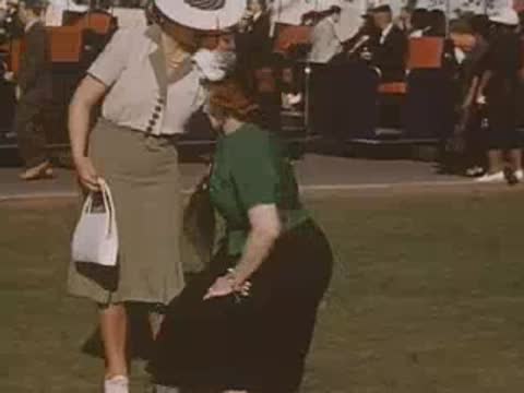 Woman crouching to adjust her shoe while speaking with another visitor