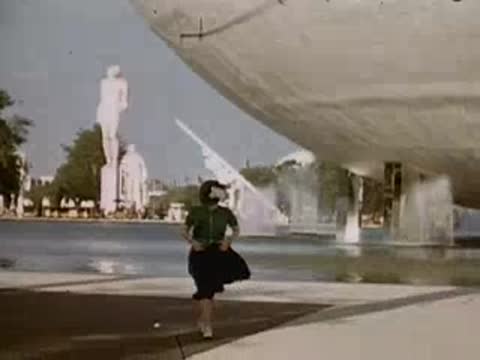 Visitors walking near modern curved exposition buildings and fountains