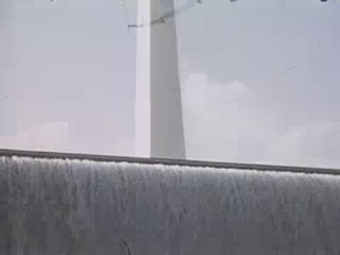 Water cascading down a wall next to a tall white spire