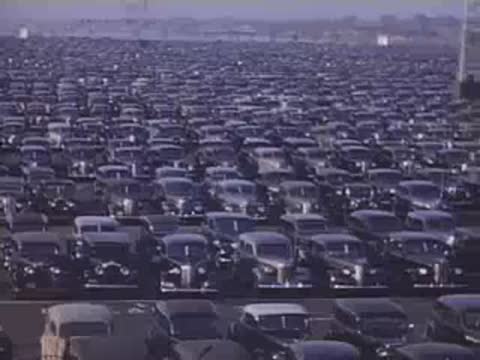 Wide shot panning over endless rows of parked vintage cars in a large parking area.