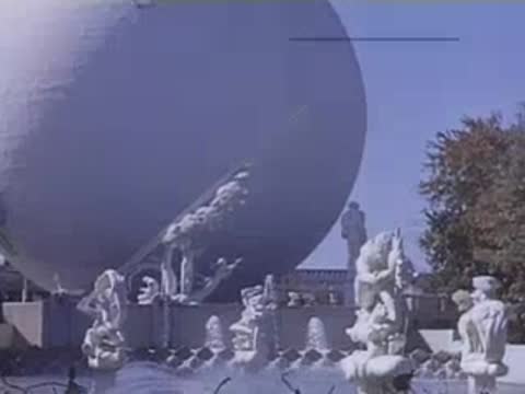 A view of fountains spraying water in front of the massive spherical Perisphere and statue groups.