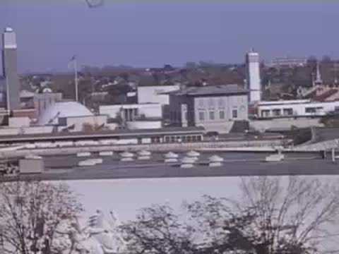An elevated view showing rooftops, cylindrical towers, and distant pavilions of the exhibition grounds.