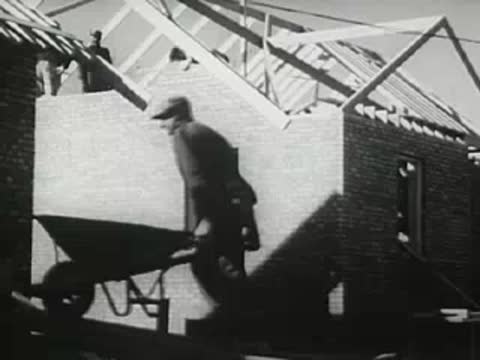 Construction worker pushing a wheelbarrow at a brick building site