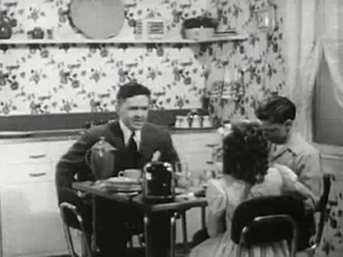 Family in a 1940s kitchen eating breakfast together around a table