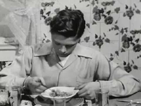Young boy eating cereal from a bowl at the kitchen table