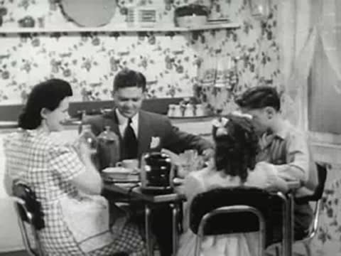 Family seated around the kitchen table having breakfast, 1940s