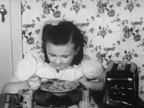 Young girl eating breakfast at table in kitchen, 1940s style