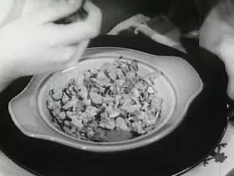 Close-up of bowl of cereal being prepared with milk, 1940s