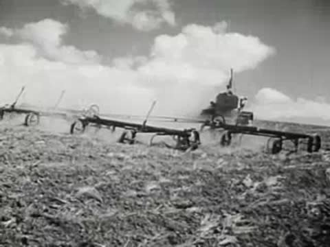 Agricultural machinery harrowing a field under cloudy sky