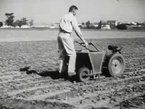 Farmer operating small motorized cart in a field, 1940s