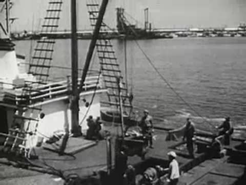 Ship at dock with crew members working on deck, 1940s
