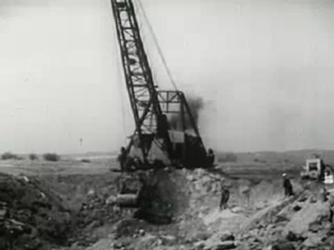 Large construction crane operating at excavation site, 1940s