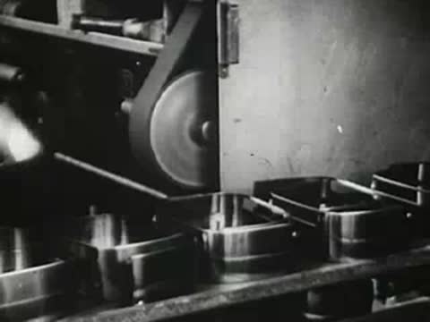 Machinery shaping and polishing metal parts on a factory production line, vintage footage.