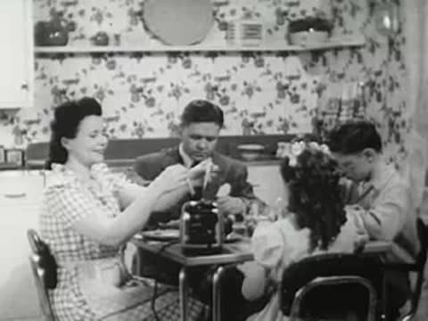 Family having breakfast at a table with a toaster, vintage domestic scene.