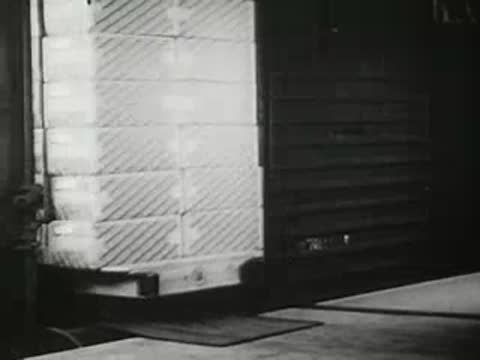 Factory worker loading stacked boxes onto a pallet inside a shipping area, vintage film.