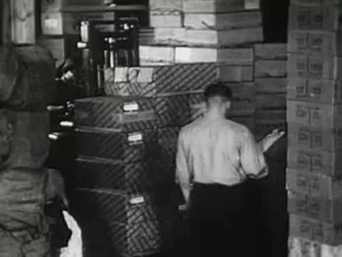 Workers in a warehouse stacking and moving boxes of merchandise, vintage footage.