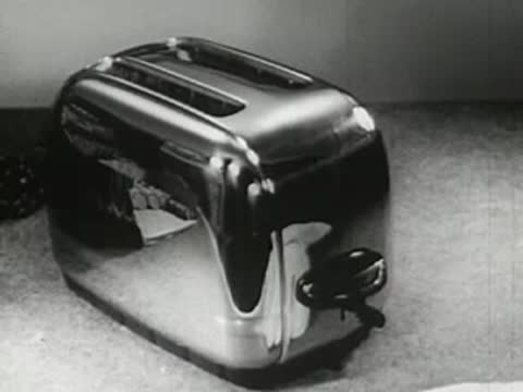 Close-up of a shiny chrome toaster on a display surface, vintage commercial film.