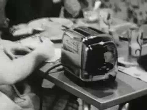 Toaster on a table during family breakfast scene in a kitchen, 1940s film.