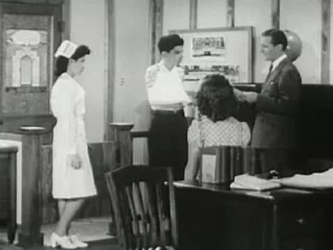 People in office talking near desk, 1940s.