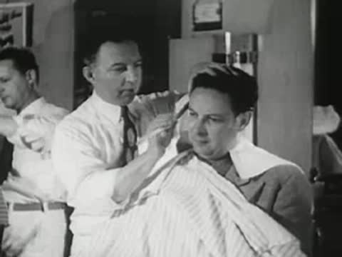 Barber cutting customer's hair in shop, 1940s.